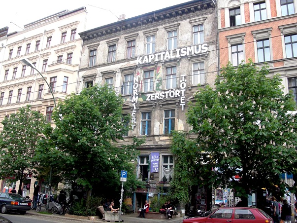 A building in Prenzlauer Berg that is surrounded by renovated buildings. It has been left like this most likely because it hasn't been possible to find it's lawful owner or their beneficiaries. The writing on the building: Capitalism - standardizes, destroys and kills.